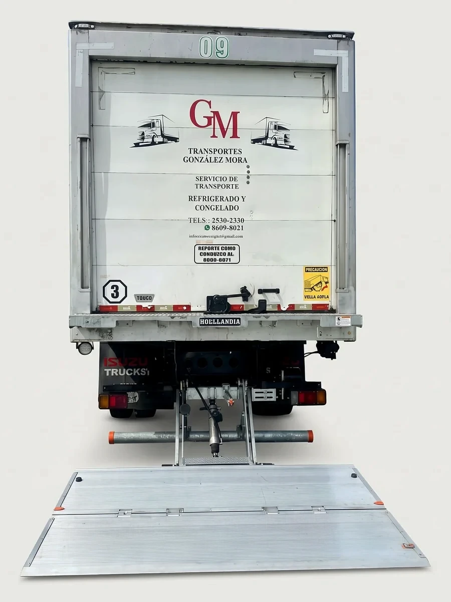 Parte trasera de un camión de Transportes González Mora con la rampa hidráulica desplegada hasta el suelo.